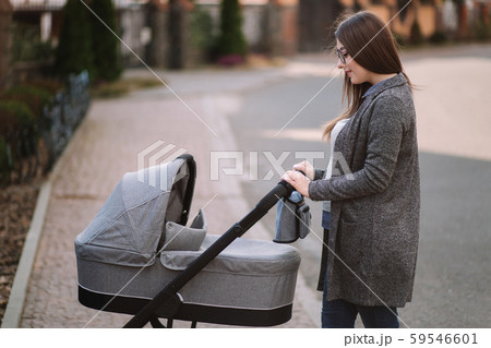 Family, child and parenthood concept - Happy mother with stroller in the park. Mom with sunglasses Family, child and parenthood concept - Happy mother with stroller in the park. Mom with sunglasses 59546601