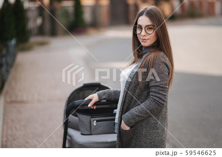 Family, child and parenthood concept - Happy mother with stroller in the park. Mom with sunglasses 59546625