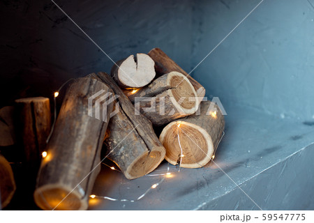 Logs of a tree are located on the wall. Imitation of a fireplace in the wall, lights of a garland 59547775