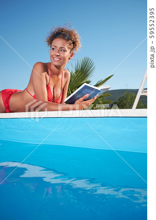 Woman reading by the swimming pool 59552395