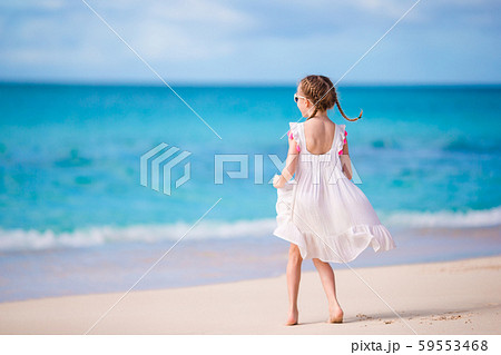 Cute little girl in white dress at beach during caribbean vacation Cute little girl in white dress at beach during caribbean vacation 59553468