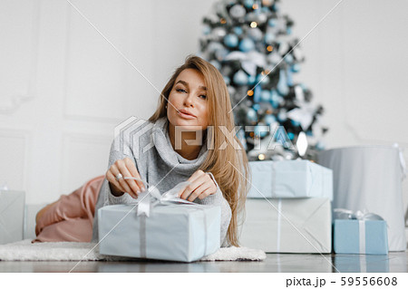 girl opens gifts near a New Year tree lying on the floor 59556608