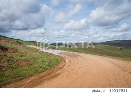 Country road in the mountains with cloudy sky 59557931