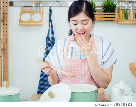 Asian woman in kitchen.smile teeth girl wearing pin apron with fruit and tablet on table prepare healthy food feeling happy Asian woman in kitchen.smile teeth girl wearing pin apron with fruit and tablet on table prepare healthy food feeling happy 59559332