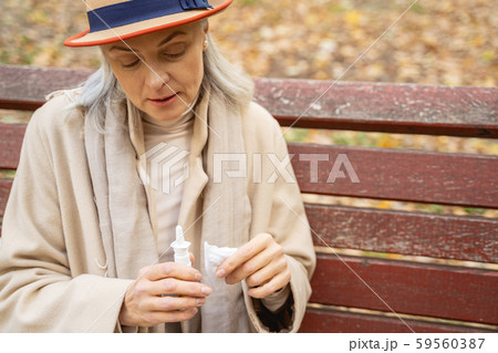 Low-spirited lady staring at her nasal spray Low-spirited lady staring at her nasal spray 59560387
