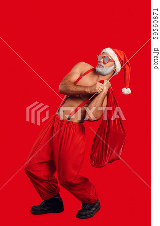 Christmas Freestyle. Young bearded Santa Claus bare muscular upper body in hat and sunglasses 59560871