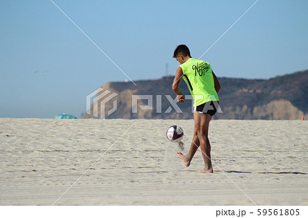 ビーチでリフティングをする外国人プロサッカー選手の後ろ姿 1の写真素材