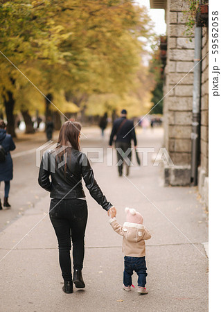 Mom walk with daughter in the public park. Happy little girl walking outside with mother 59562058