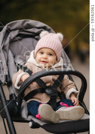 Cute little baby in pram. Adorable baby girl in autumn sitting in her pram 59562061
