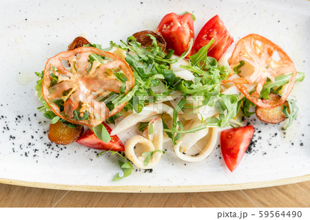 Fresh Salad with calamari, mushrooms, tomatoes and fried potato on wooden background. Seafood salad 59564490
