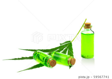 Hand holding a glass bottle with CBD oil and cannabis leaf at the Hand holding a glass bottle with CBD oil and cannabis leaf at the 59567741