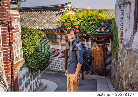 Young man tourist in Bukchon Hanok Village is one of the famous place for Korean traditional houses Young man tourist in Bukchon Hanok Village is one of the famous place for Korean traditional houses 59573177