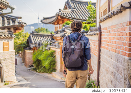 Young man tourist in Bukchon Hanok Village is one of the famous place for Korean traditional houses Young man tourist in Bukchon Hanok Village is one of the famous place for Korean traditional houses 59573434