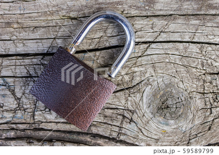 A padlock lies on an old, wooden board with cracks and scratches 59589799