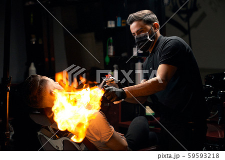 Portrait of barber giving hair fire treatment to his client Portrait of barber giving hair fire treatment to his client 59593218
