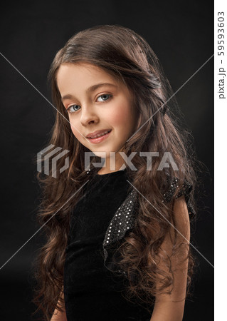 Cute girl with curly hair looking at camera and smiling. 59593603