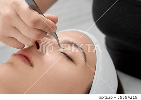 Woman undergoing eyelash extensions procedure. 59594219