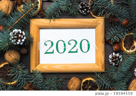 Frame of Christmas tree cones oranges nuts on dark wooden background. The inscription 2020. Frame of Christmas tree cones oranges nuts on dark wooden background. The inscription 2020. 59594559