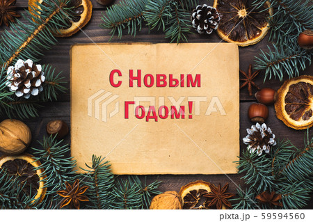 Frame of Christmas tree cones oranges nuts on dark wooden background. Inscription in Russian Happy New Year. Frame of Christmas tree cones oranges nuts on dark wooden background. Inscription in Russian Happy New Year. 59594560