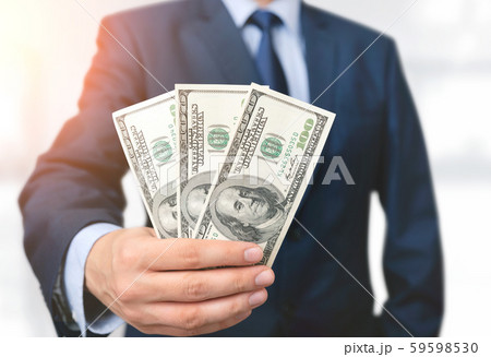 Man in a suit holds hundred dollar banknotes 59598530