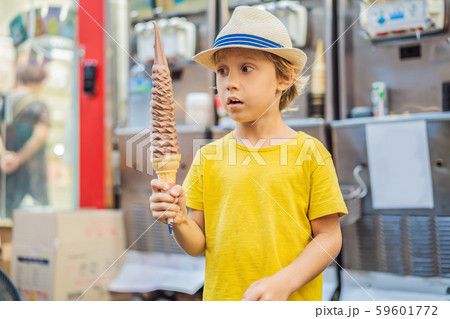 Little tourist boy eating 32 cm ice cream. 1 foot long ice cream. Long ice cream is a popular 59601772
