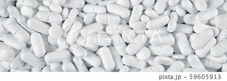 White pills spilled on blue wooden background 59605913