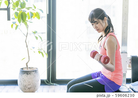 ダンベルで腕の筋肉上腕三頭筋を鍛える真剣な表情の若い女性 ダンベルで腕の筋肉上腕三頭筋を鍛える真剣な表情の若い女性 59606230