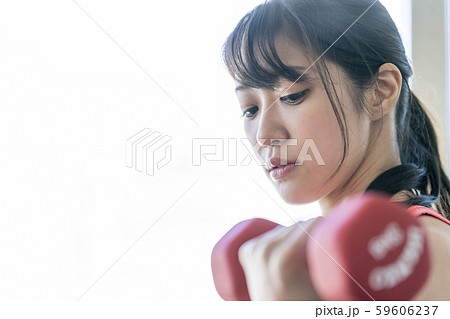 ダンベルで腕の筋肉上腕三頭筋を鍛える真剣な表情の若い女性 ダンベルで腕の筋肉上腕三頭筋を鍛える真剣な表情の若い女性 59606237