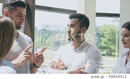 Small company of two men and two women in an office in a small talk with each other 59609412