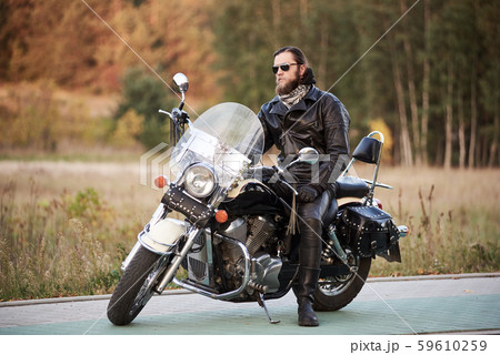 Bearded biker in black leather jacket on modern motorcycle on country roadside. 59610259