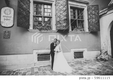 Wedding photo shooting. Bride and bridegroom walking in the city. Married couple embracing and 59611115