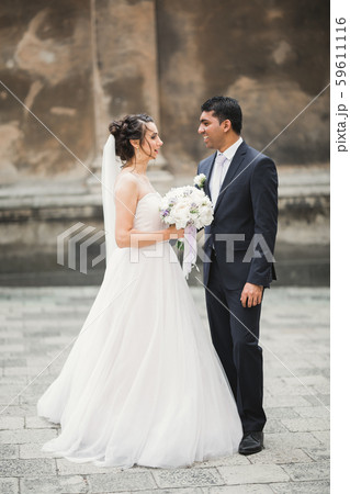 Gorgeous happy couple standing close to each other and looking in eyes at old city background 59611116