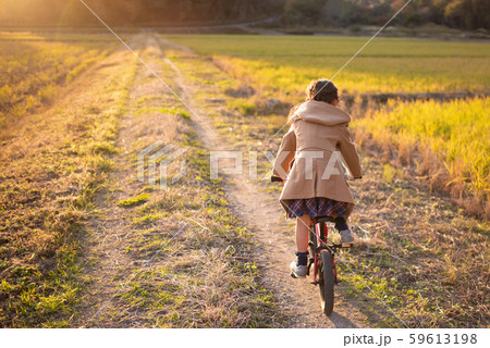 夕焼けの小道を進む自転車に乗った女の子 59613198