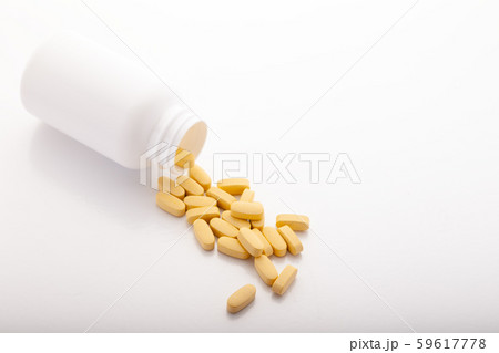 Closeup scattered from white pill bottle orange oval medicine vitamins for pregnancy, pills, drugs Closeup scattered from white pill bottle orange oval medicine vitamins for pregnancy, pills, drugs 59617778