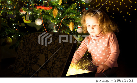 Kid by Christmas tree opens magic chest. Child Kid by Christmas tree opens magic chest. Child 59621553