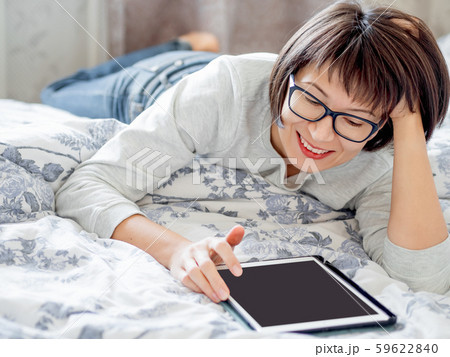 Woman in glasses are lying in bed with tablet. She is touching screen. Morning bedtime. Woman in glasses are lying in bed with tablet. She is touching screen. Morning bedtime. 59622840