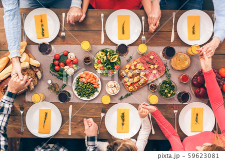 People sitting at home behind table, praying together before dinner 59623081