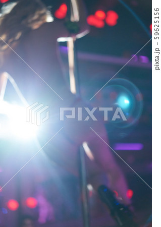 Image out of focus. Young sexy woman pole dancing striptease with pylon in night club. Beautiful 59625156