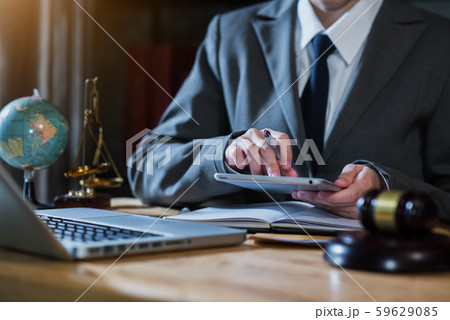 Justice and law concept.Male judge in a courtroom the gavel, working with digital tablet computer on wood table in sun light. 59629085