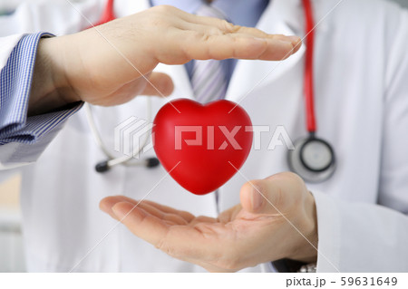 Doctor hold in hand red toy hert against hospital 59631649
