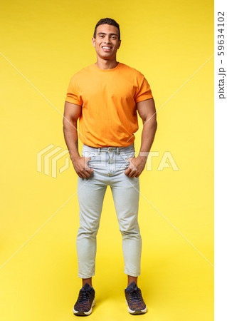 Vertical full-length studio shot young hipster guy with mascular body, standing orange t-shirt and Vertical full-length studio shot young hipster guy with mascular body, standing orange t-shirt and 59634102
