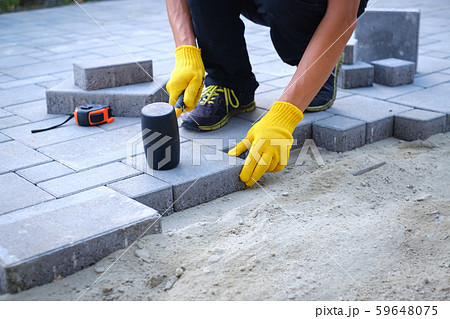 The master in yellow gloves lays paving stones 59648075