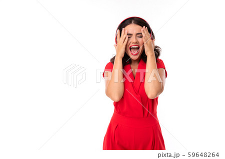A young woman with red lips listens to music in headphones and screams 59648264