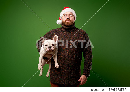 Surprised man in santa hat with bulldog on empty green background Surprised man in santa hat with bulldog on empty green background 59648635