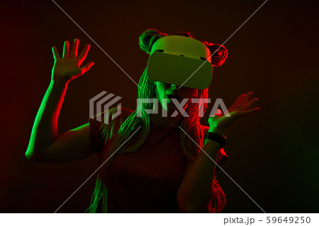 Woman is using virtual reality headset. Neon light studio portrait. Woman is using virtual reality headset. Neon light studio portrait. 59649250