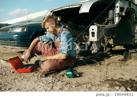 Male mechanic in welding glasses on car junkyard 59649831