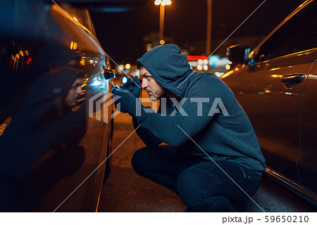 Car thief with screwdriver breaking door lock Car thief with screwdriver breaking door lock 59650210