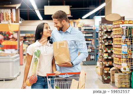 Daily Shopping. Couple in the supermarket walking with cart together looking at each other cheerful Daily Shopping. Couple in the supermarket walking with cart together looking at each other cheerful 59652557