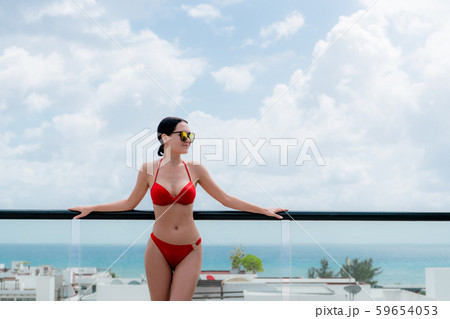 Happy woman beside a rooftop pool with a beautiful city and ocean view on background 59654053