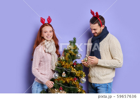 Pretty couple decorating Christmas tree Pretty couple decorating Christmas tree 59657636